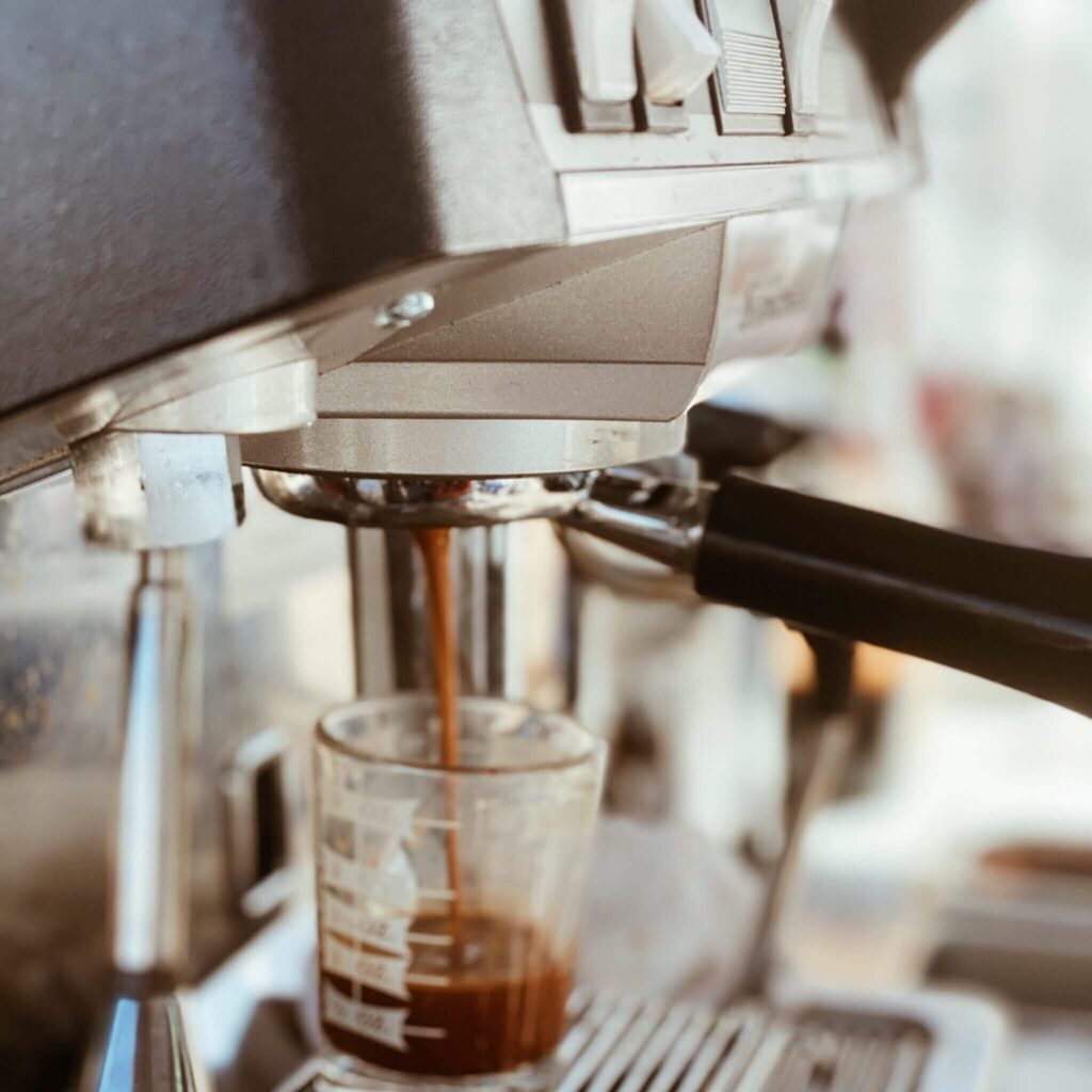 Close-up of espresso being brewed from a professional espresso machine into a measuring glass, highlighting mobile coffee catering services